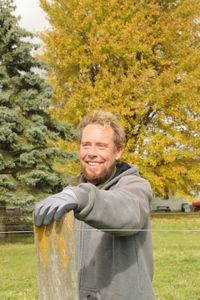 Ben Reinhold smiles while fixing one of the Pol family farm's animal pasture fence posts. (National Geographic)