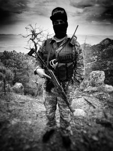 A masked narco stands guard with a rifle in Sinaloa mountains. (Nick Quested)