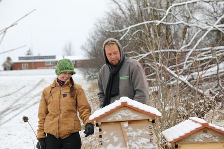 Beth Pol and Ben Reinhold look at the Pol family farm's bee hives covered in snow. (National Geographic)