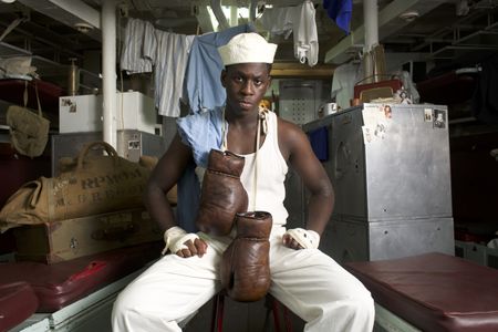 Mess attendant Doris Miller (played by Abdul Sulaiman) pursued boxing as a sport. Here, Miller is pictured in a WW2 historic reenactment scene for "Erased: WW2's Heroes of Color. The series tells the stories of three Black heroes who miraculously survived the attack on Pearl Harbor. Miller served as mess attendant on the USS West Virginia, where he pursued boxing as a sport. He defied racial stereotypes when he shot down enemy planes during the attack. (National Geographic/Seye Isikalu)