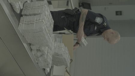 CBP Officer Johnson counts and inspect stacks of counterfeit currency they discovered inside a shipment in Philadelphia. (National Geographic)