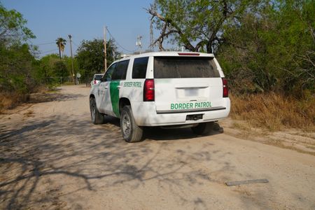 A Border Patrol vehicle is parked on a dirt road near the border wall in the Rio Grande Valley, Texas. (National Geographic)