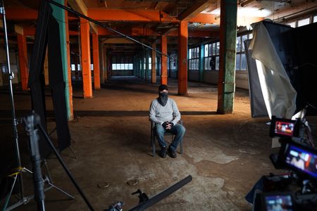 In this behind-the-scenes photo, member of the 4th Eye Corporation "Valak" wears a scarf obscuring the bottom half of his face to pose for a portrait during the production of "Killer Lies: Chasing a True Crime Con Man," a documentary series about obsession and deception, following the unraveling of Stephane Bourgoin’s career as a best-selling author and serial killer expert. "Valak" is a pseudonym; he chose to remain anonymous. (National Geographic/Ben Selkow)