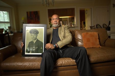 Frank Bland holds a portrait of his father, George Bland, at his home in Richmond Virginia. "Erased: WW2's Heroes of Color" tells the stories of three Black heroes who miraculously survived the attack on Pearl Harbor. One of these men is George Bland, who served as mess attendant on the USS West Virginia. (National Geographic/Nelson Adeosun)