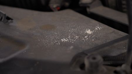 An unknown white powdery substance is sitting loosely inside of the hood of a suspect's vehicle.(National Geographic)