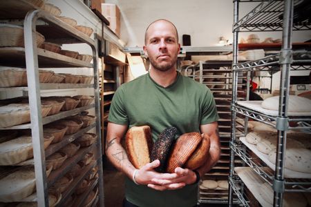 Josey Baker holds an assortment of his naturally leavened loaves. Since it opened in 2012, Josey's bakery, The Mill, has become a popular bakery destination in San Francisco. (National Geographic/Ryan Rothmaier)