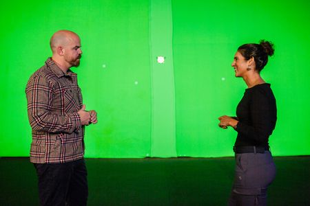 Nick Payne and Diva Amon conversing in front of the studio greenscreen. (National Geographic/Aubrey Fagon)