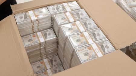 CBP Officers Pirollo and Johnson open and inspect stacks of counterfeit currency they discovered inside a shipment in Philadelphia. (National Geographic)