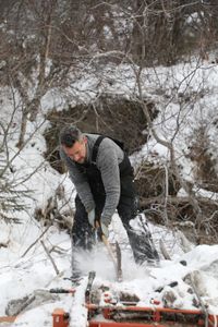 Joel Jacko uncovers his wood cutting tool that was buried under ice and snow. (National Geographic/Lauren "Bird" Dixon)