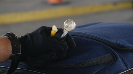 A CBP officer holds drug paraphernalia found among a passenger's belongings in El Paso. Texas. (National Geographic)