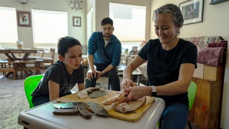 Ana Hoffman shows her nephew, Jaxon how to fillet a fish. (BBC Studios Reality Productions, LLC/Brian Bitterfeld)