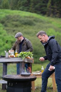 Iceland - Rain falls as Gordon Ramsay (R) cooks fresh scallops during the final cook in Iceland. Chef, Ragnar Eiríksson works on his dishes in the background. (Credit: National Geographic/Justin Mandel)