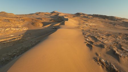 Film crew 4x4 at the bottom of a dune on the Skeleton coast.  (credit: National Geographic/Tom Beldam)