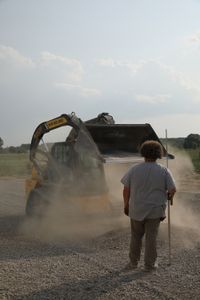 Andrew Hutton watches Ben Reinhold as he drives a compact track loader full of gravel while working on a swale to prevent flooding around the sheep hut. (National Geographic)