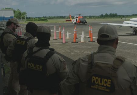 Helicopter's propellers turn as four CBP Agents stand on the side of the tarmac runway of a CBP Airfield  in Mayaguez, PR. (Lucky 8 TV)