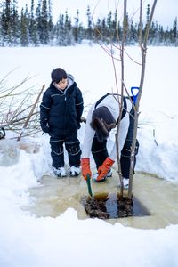 Ricko DeWilde teaches his son Keenan DeWilde how to properly set a beaver trap under the ice. (BBC Studios Reality Productions/v)