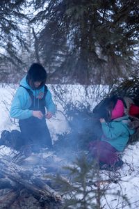 Ricko DeWilde cooks dinner over an open fire in the woods with his daughter, Maya DeWilde. (BBC Studios Reality Productions, LLC/Ryan Walsh)