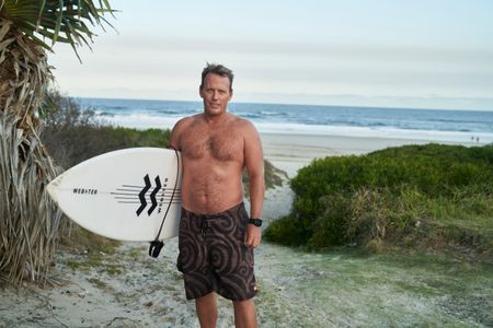 Lee Jonsson with his surfboard at Shelly Beach. (National Geographic/Justine Kerrigan)