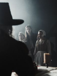 A young man stands guard over two accused witches, both of whom are facing the council in front of them.(Dash Productions Services LTD/Antoan Ivanov)