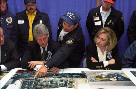 President Bill Clinton and First Lady Hillary Rodham Clinton meet with the heads of the search and rescue teams for a briefing held at the Oklahoma State Fairgrounds arena on the day of the memorial service for the victims of the truck bombing of the Alfred P. Murrah Federal Building. Chief Gary Marrs from the Oklahoma City Fire and Rescue department stands between the President and First Lady and points to an area on an enlarged photo of the building remains at the bombing site. (Ralph Alswang/William J. Clinton Presidential Library)