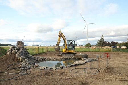 Ben Reinhold operates a mini excavator to continue working on the Pol family farm's new pond. (National Geographic)