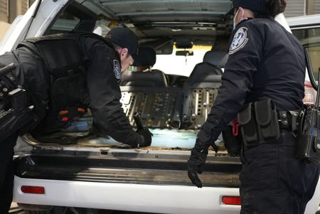 CBP Officers Hernandez and Hoffman work to dismantle the trunk of a suspect's vehicle in search of smuggled drugs in Calexico, Calif. (National Geographic)