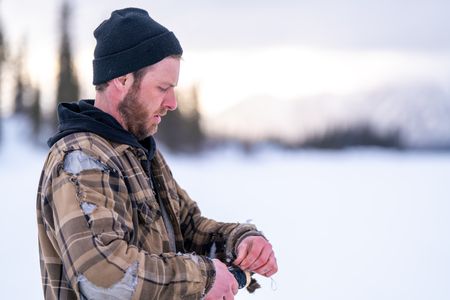 Johnny Rolfe sets a line for burbot underneath the frozen ice. (BBC Studios Reality Productions/Patrick Henderson)