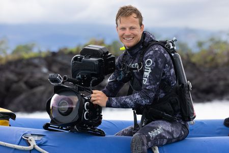 Bertie Gregory in dive gear with an underwater camera sitting on the edge of a small rib preparing to dive. (credit: National Geographic/Zubin Sarosh)