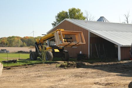 Andrew Hutton drives a telehandler, carrying wooden frames, into the Pol family farm's new garden. (National Geographic)