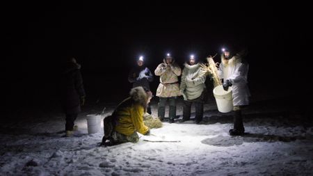 Agnes Hailstone, and her daughters, Tinmiaq, Mary, Iriqtaq, Qutan, and Carol ice fish in the dark during winter. (BBC Studios/Dwayne Fowler)