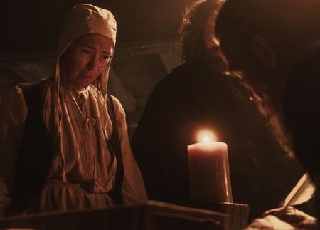 A woman being interrogated by Hopkins and Stearne stares into a candle flame in fear.(Dash Productions Services LTD/Antoan Ivanov)