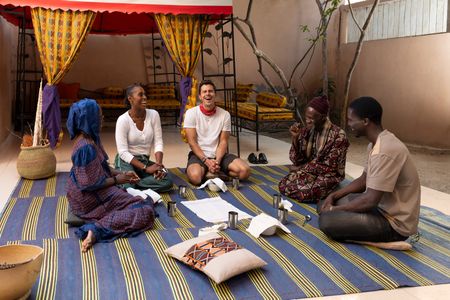 Fatima Fall, Issa Rae, Antoni Porowski, Papa Abdoulaye Sene and Hamade Ndiaye gather and wait for the Ceebu jën. (National Geographic/John Wendle)