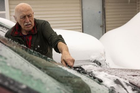 Dr. Pol clears off the snow off his windshield in order to head to an emergency farm call. (National Geographic/Mike Stankevich)