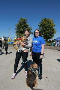 Vet techs Laurel Driver and Katelyn Fischer smile with their dogs at a 5K event. (National Geographic)