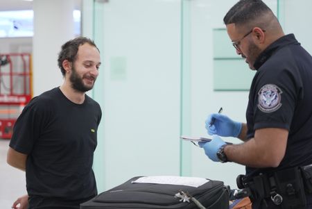 CBP Officer De La Cruz questions a traveler while they inspect the traveler's luggage at the Philadelphia International Airport in Philadelphia, Pa.  (National Geographic)