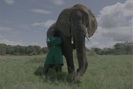 Phillip Okode leaning on Murera the elephant. (Big Wave Productions)