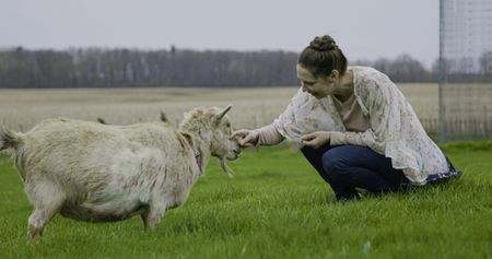 Beth Pol plays with the family's goat, Nono, at Pol Family Farm. (National Geographic)