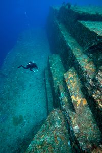 A diver examines the sandstone structure of the undersea Yonaguni Monument. MYSTERIOUS ISLANDS takes viewers on an unforgettable adventure to explore the most extraordinary and enigmatic islands on the planet. (Credit: MICHAEL PITTS/NATURE PICTURE LIBRARY/SCIENCE PHOTO LIBRARY)