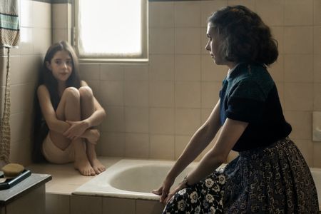 A SMALL LIGHT - Liddy, played by Audrey Kattan, sits in the bathroom with Miep, played by Bel Powley, in A SMALL LIGHT. (Credit: National Geographic for Disney/Dusan Martincek)