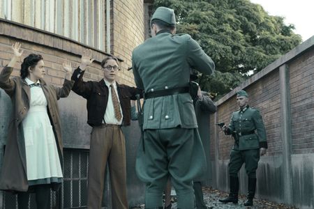 A SMALL LIGHT - Nurse Betje, played by Hannah Bristow, Jan Gies, played by Joe Cole, and others are held up at gunpoint by German soldiers as seen in A SMALL LIGHT. (Credit: National Geographic for Disney/Dusan Martincek)