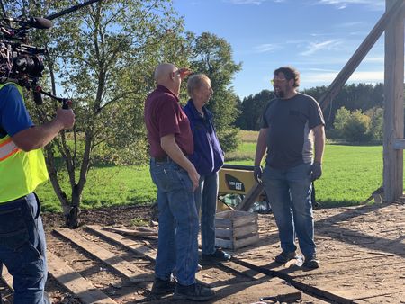 Dr. Pol and Diane Pol visit Charles Pol at the site of the old barn they are taking down, while a crew member films. (National Geographic)