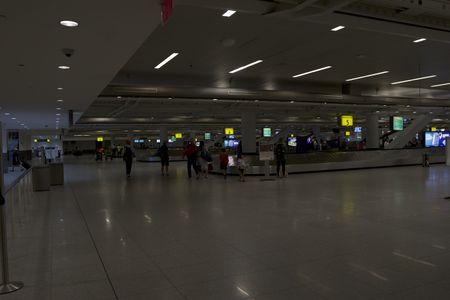 Multiple traveler's are standing around the baggage claim area of the JFK International Airport in order to retrieve their luggage. (National Geographic)