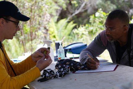Christian Cooper writes down measurements as avian technician Bret Nainoa Mossman examines a forest bird at the Pu'u Maka'ala Natural Area Reserve. (National Geographic for Disney/Troy Christopher)
