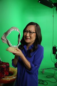 Helen Hong giving a scared look while holding a display shark jaw. (National Geographic/Robert Toth)