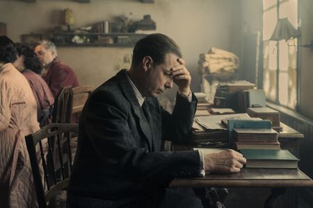 A SMALL LIGHT - Dr. Pfeffer, played by Noah Taylor, reads in the annex as seen in A SMALL LIGHT. (Credit: National Geographic for Disney/Dusan Martincek)