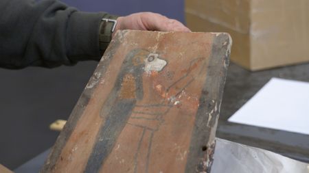 CBP Officer Liu holds a piece of a damaged Egyptian canopic box after it was discovered in a shipment at the JFK International Airport in New York. (National Geographic)