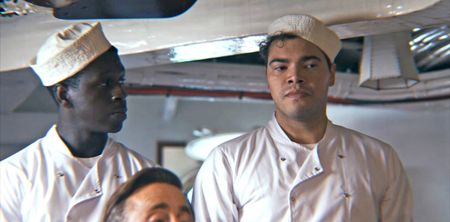 Doris Miller and George Bland (played by Abdul Sulaiman and Daniel Abbott, respectively) attend to White officers onboard the USS West Virginia in a WW2 historic reenactment scene for "Erased: WW2's Heroes of Color. The series tells the stories of three Black heroes who miraculously survived the attack on Pearl Harbor. Miller and Bland served as mess attendants on the USS West Virginia. (National Geographic)