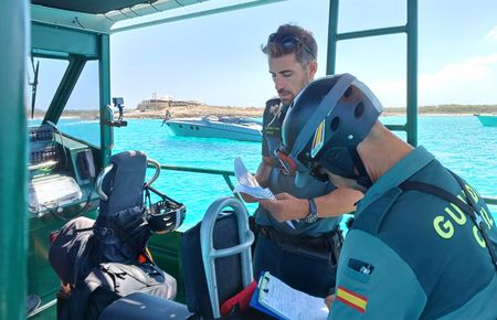 Saer and Garvi, Guardia Civil officers, check the license of a boat. (National Geographic/Jose Antonio Gavilán Tobal)