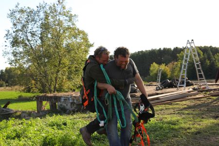 Ben Reinhold laughs and jumps onto Charles Pol's back to celebrate the completion of the old barn takedown. (National Geographic)