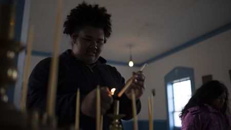 Jazmine Amodo-White lights candles inside a church. (National Geographic/Ashton Hurlburt)